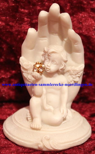 Engel auf Sockel sitzend ausgespreizten Flügeln rechten Hand Diamantkugel Hintergrund schützend Hand